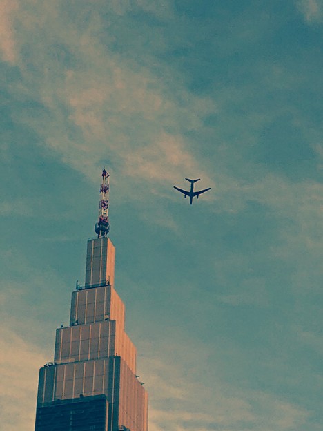 写真: ドコモタワーの横を飛ぶ飛行機