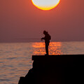 写真: 夕日と釣人