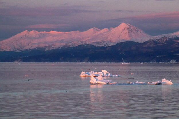 写真: 夕日を受ける残氷と知床連山
